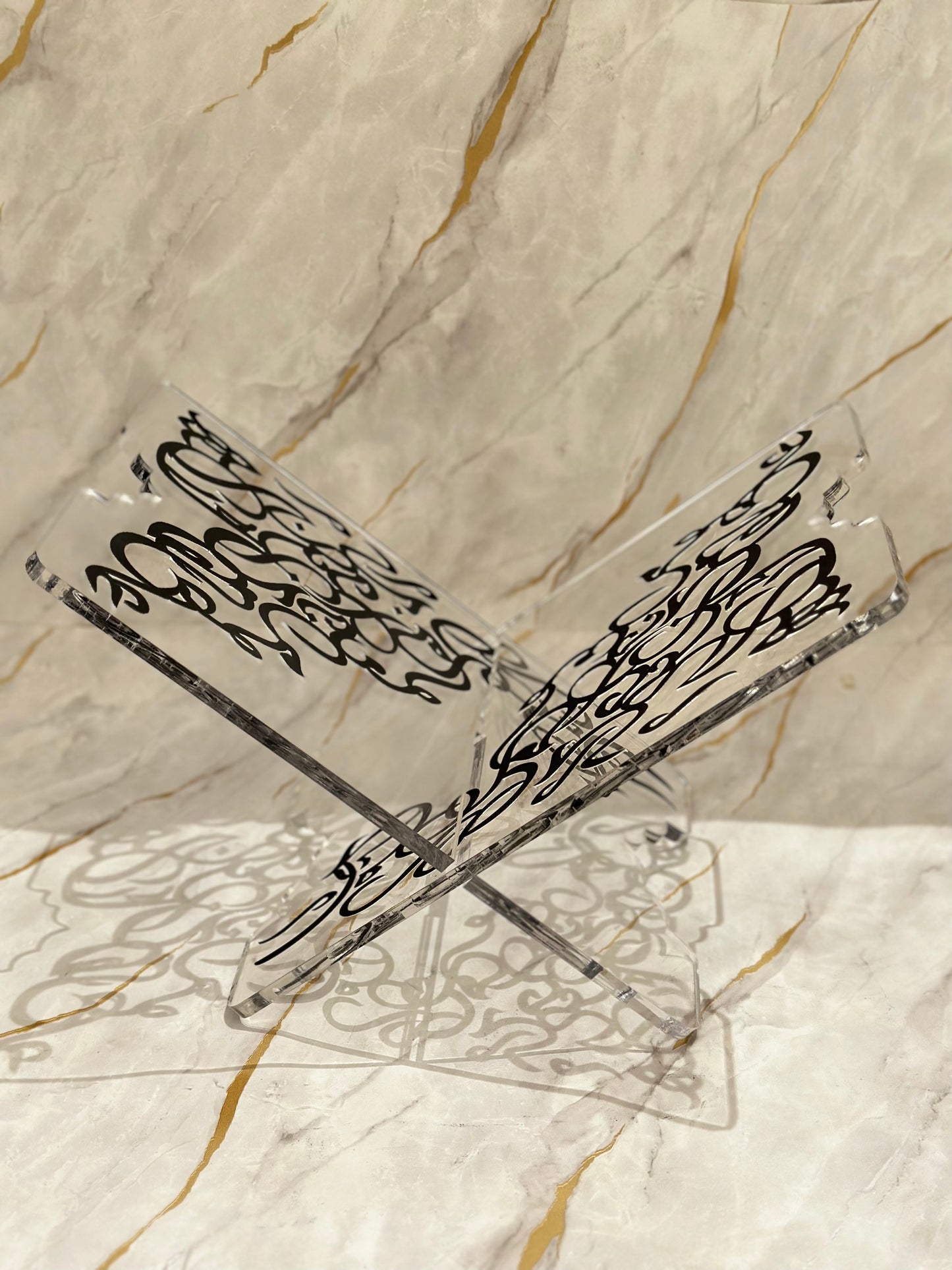 Introducing our Artisan Quran Stand, a fusion of elegance and devotion. Featuring a clear base with intricate Arabic calligraphy in striking black or radiant hammered gold, it offers a sacred setting for the Quran. Whether for personal reflection or as a decorative centerpiece, this stand enriches your spiritual space with timeless artistry.