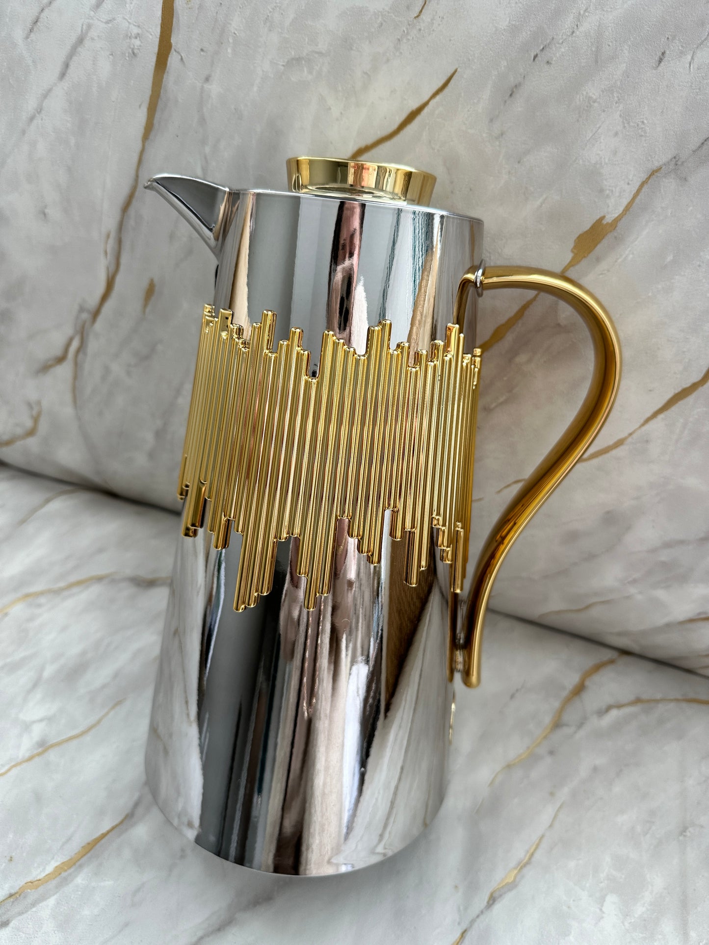 Delight in the Cascade Coffee Pot, an exquisite 1-liter creation designed for coffee aficionados. Available in opulent gold, matte charcoal, pristine white with golden marbling, or gleaming chrome, each pot features a captivating gold drip pattern that shimmers under light. Enjoy the ergonomic handle and spout for effortless pouring.