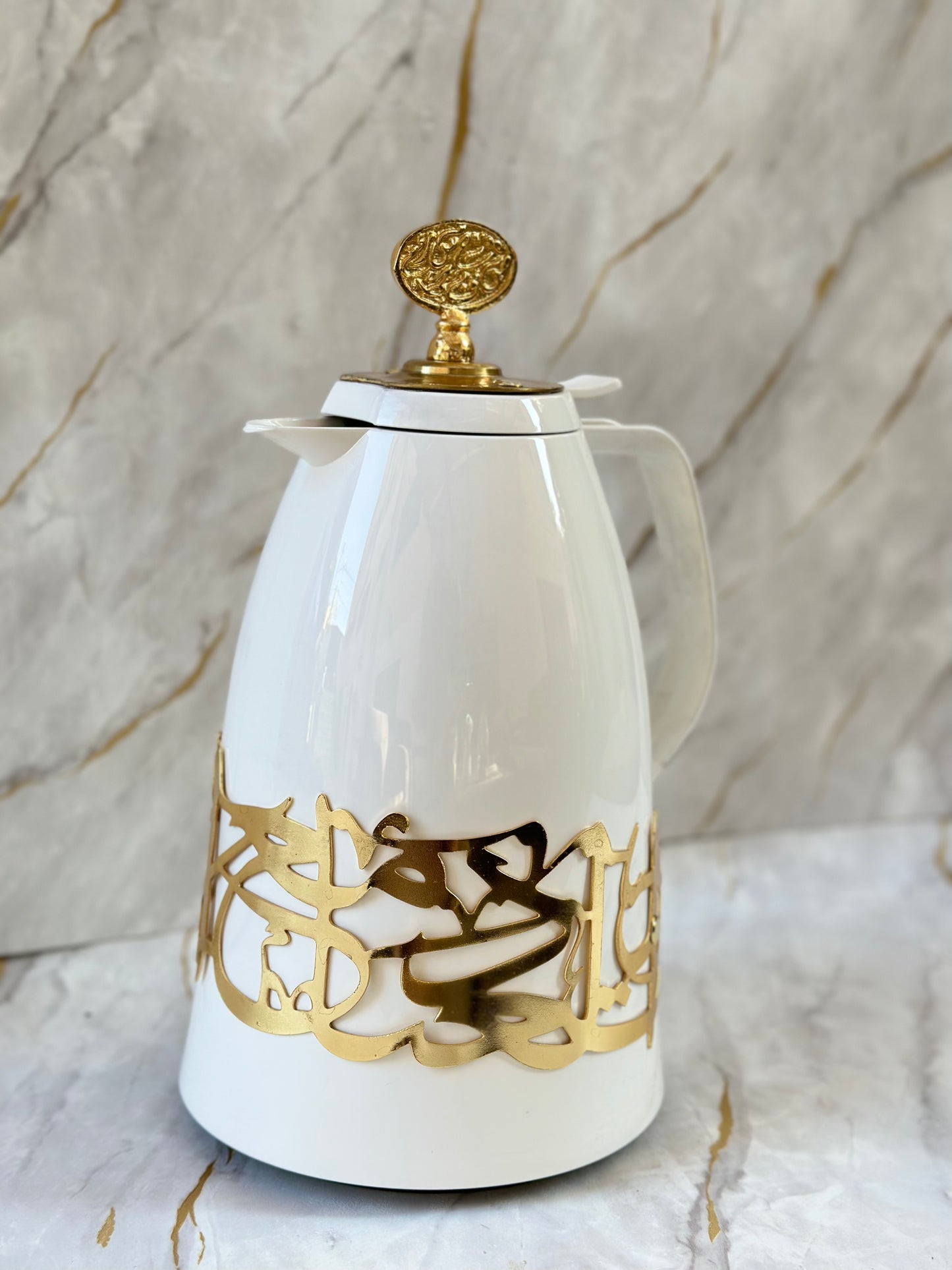 Introducing our Arabesque Coffee Flask, a fusion of German precision and Middle Eastern elegance. This sleek white flask, adorned with lustrous gold accents and intricate Arabic calligraphy, keeps your coffee warm for up to 12 hours. Perfect for coffee aficionados seeking both style and functionality, it's a luxurious addition to any home or a thoughtful gift that celebrates heritage and quality.