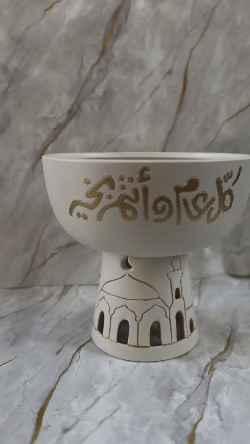 Introducing our Eid Mubarak Ceramic Bowl, a blend of artistry and spirituality. Crafted with care, it showcases golden calligraphy and mosque silhouette cutouts, offering a serene ambiance perfect for incense. Ideal for gifting or personal use during holy occasions, this piece adds a touch of elegance to any setting.