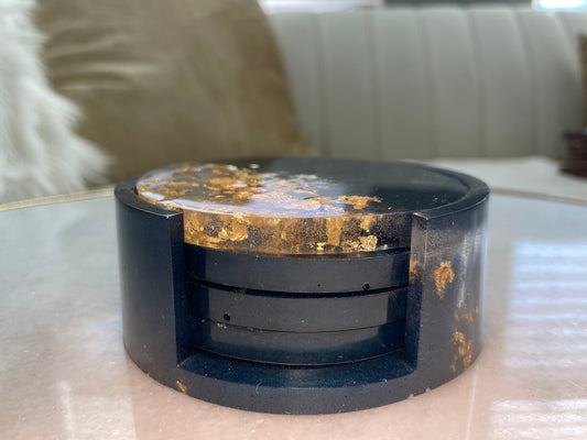 "Create a statement with this set of 4 hand-poured resin coasters from Texas, showcasing deep navy hues and shimmering gold accents. Each coaster boasts a unique design, perfect for elevating your table decor. Crafted for durability and style, these coasters measure 5-5.5 inches in diameter and come complete with non-slip bumpers. Ideal for both everyday use and special occasions, they add a touch of elegance to any setting."